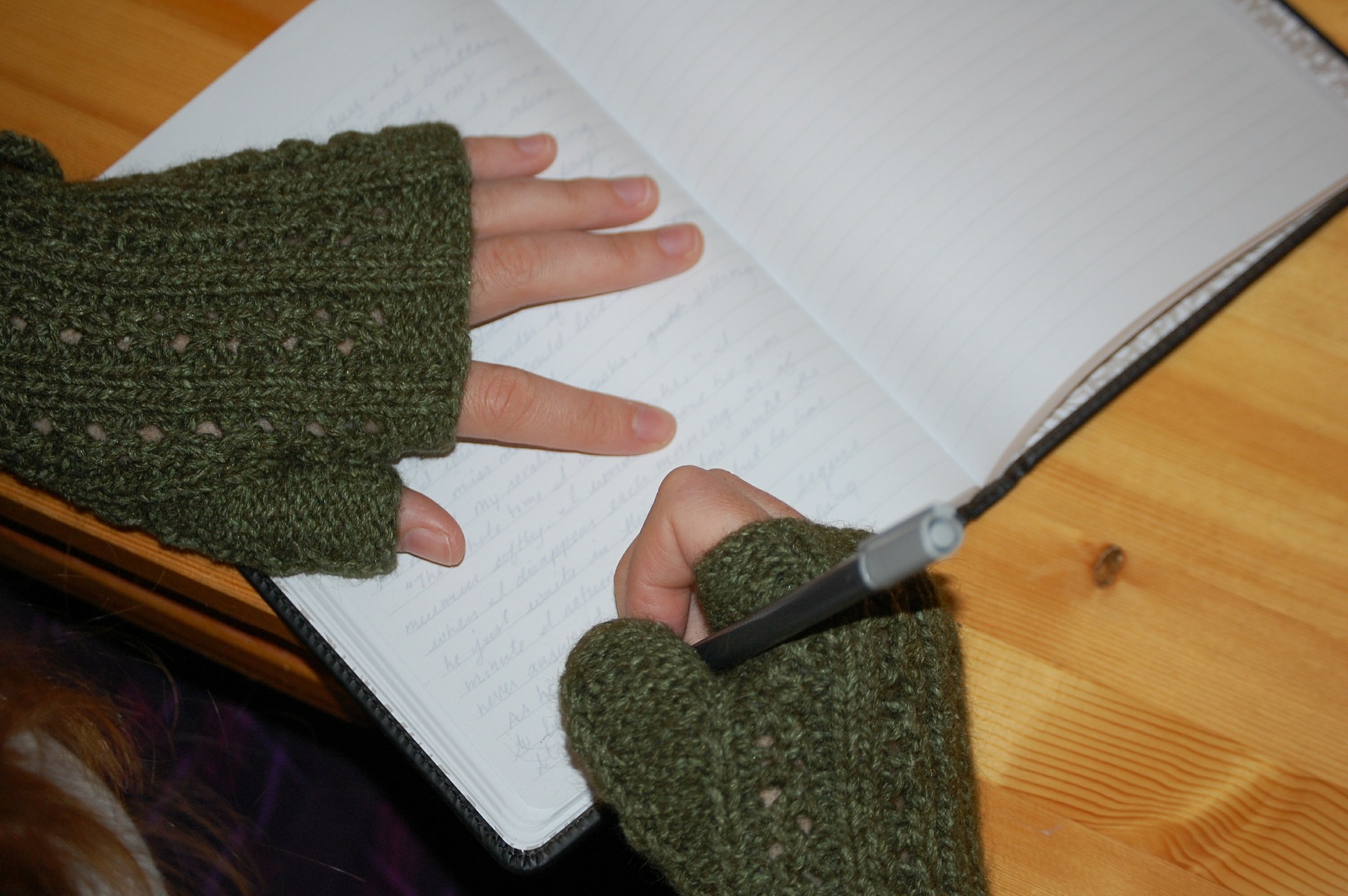 Image of person wearing gloves writing in a journal
