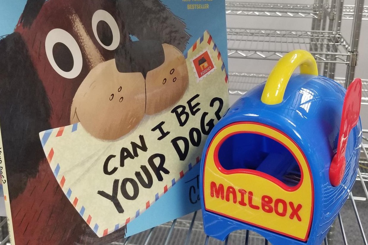 Image of book titled "Can I Be Your Dog?" and toy mailbox