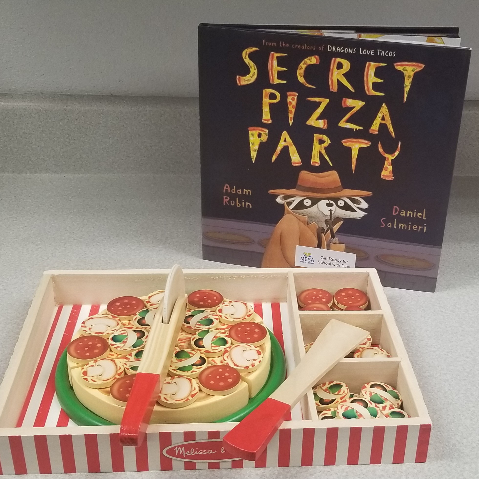 Image of wooden pizza playset and book titled "Secret Pizza Party"