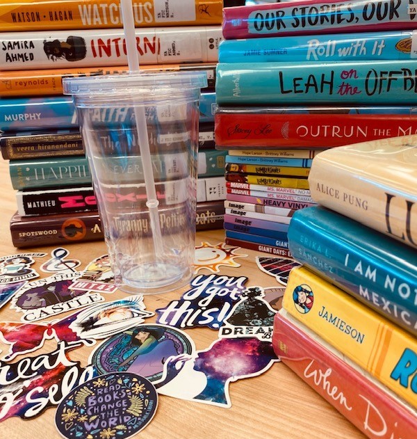 YA books and array of stickers and a clear drinking tumbler.