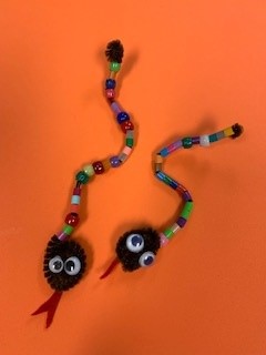 Two Pipe Cleaner and bead snakes on an orange background