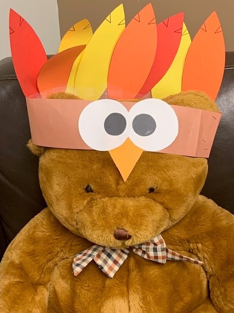 Stuffed brown bear wearing turkey headband made from construction paper