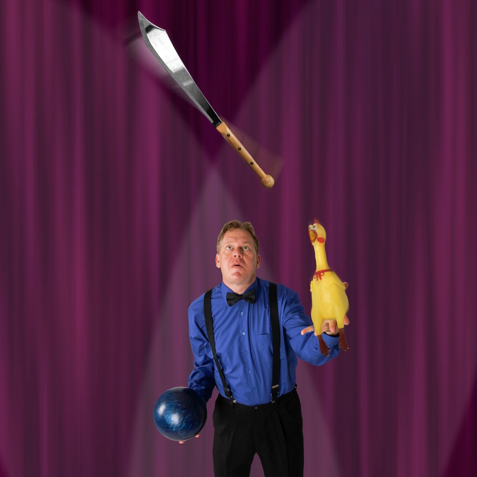 James Reid juggling a ball, rubber chicken, and a sword.