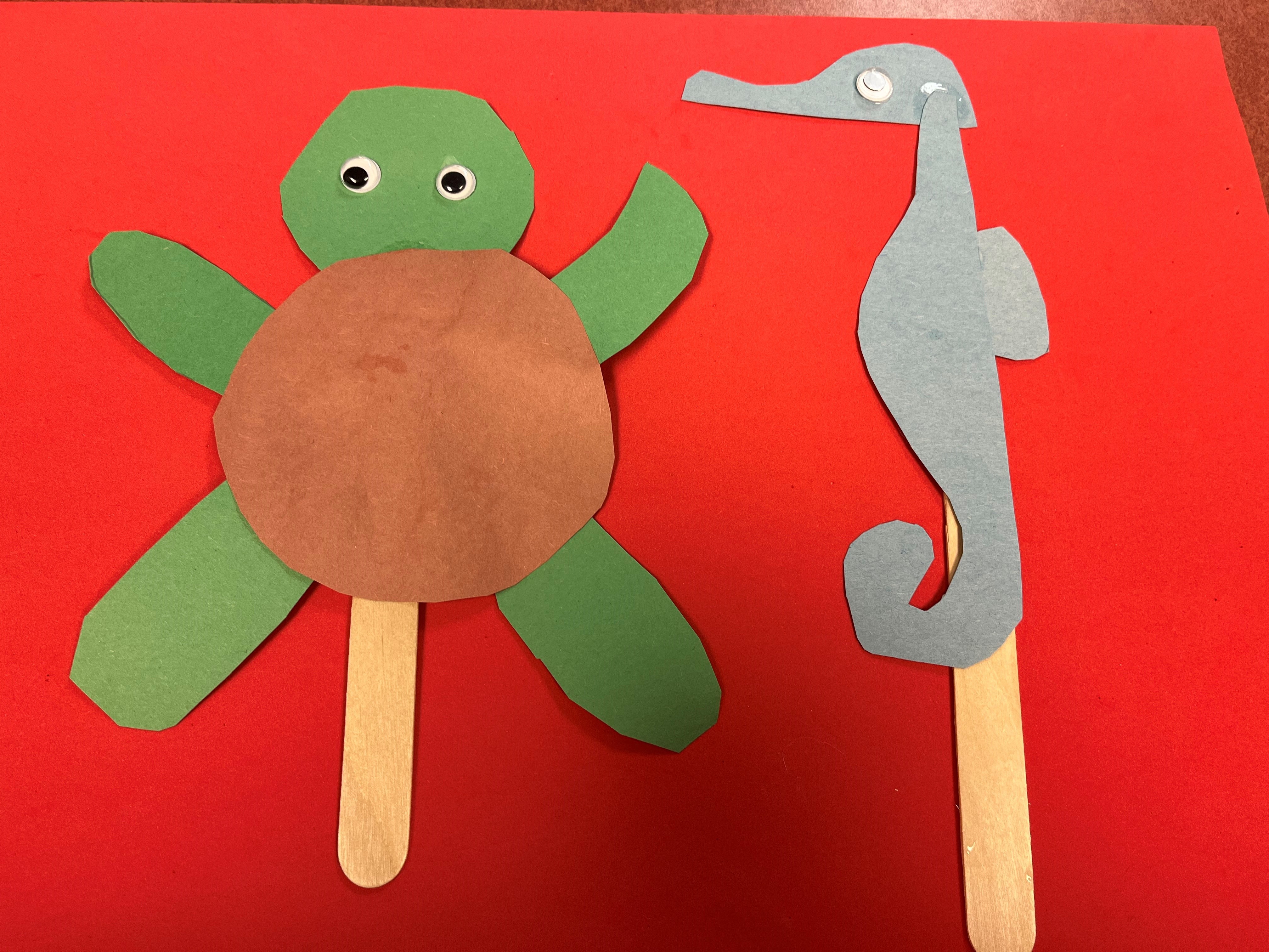 Turtle and seahorse popsicle stick with red background.