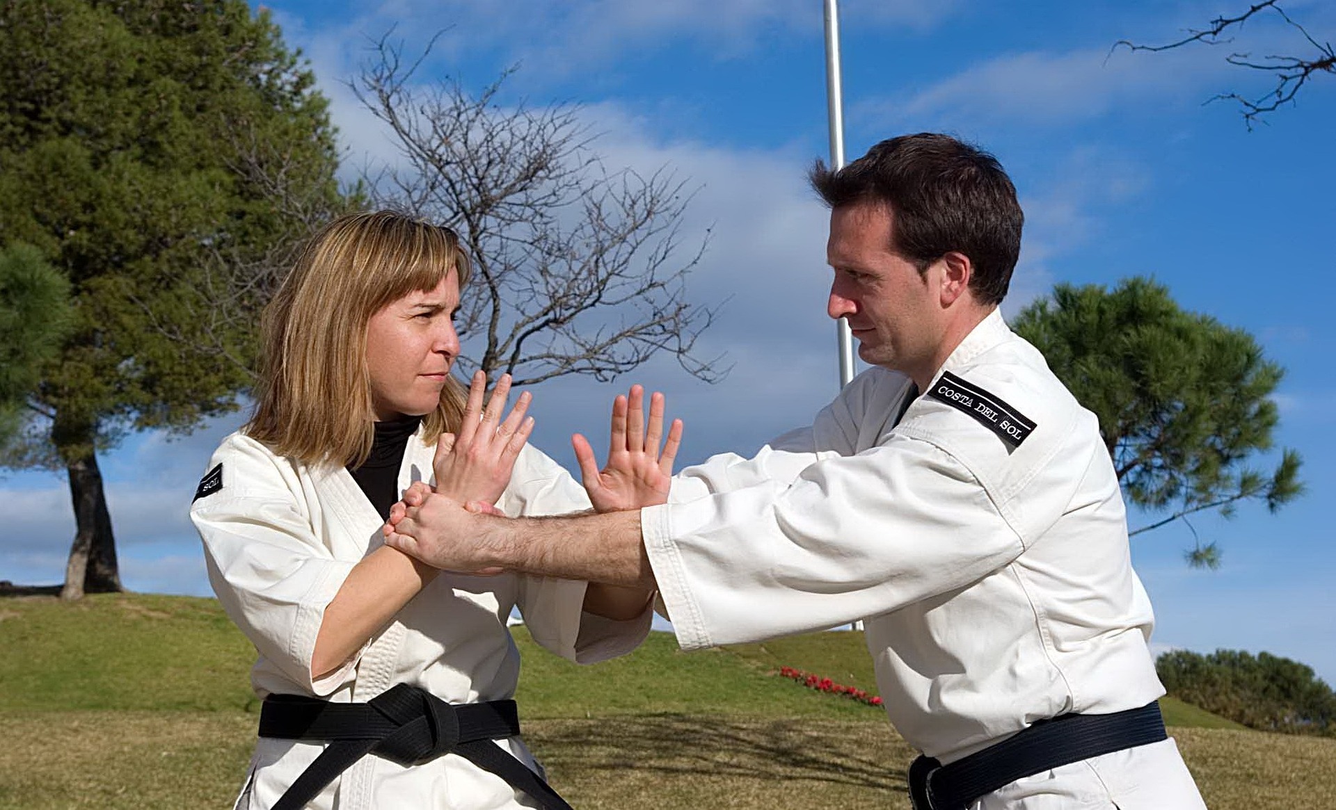 Man and woman sparring with karate gi on and black belts. 