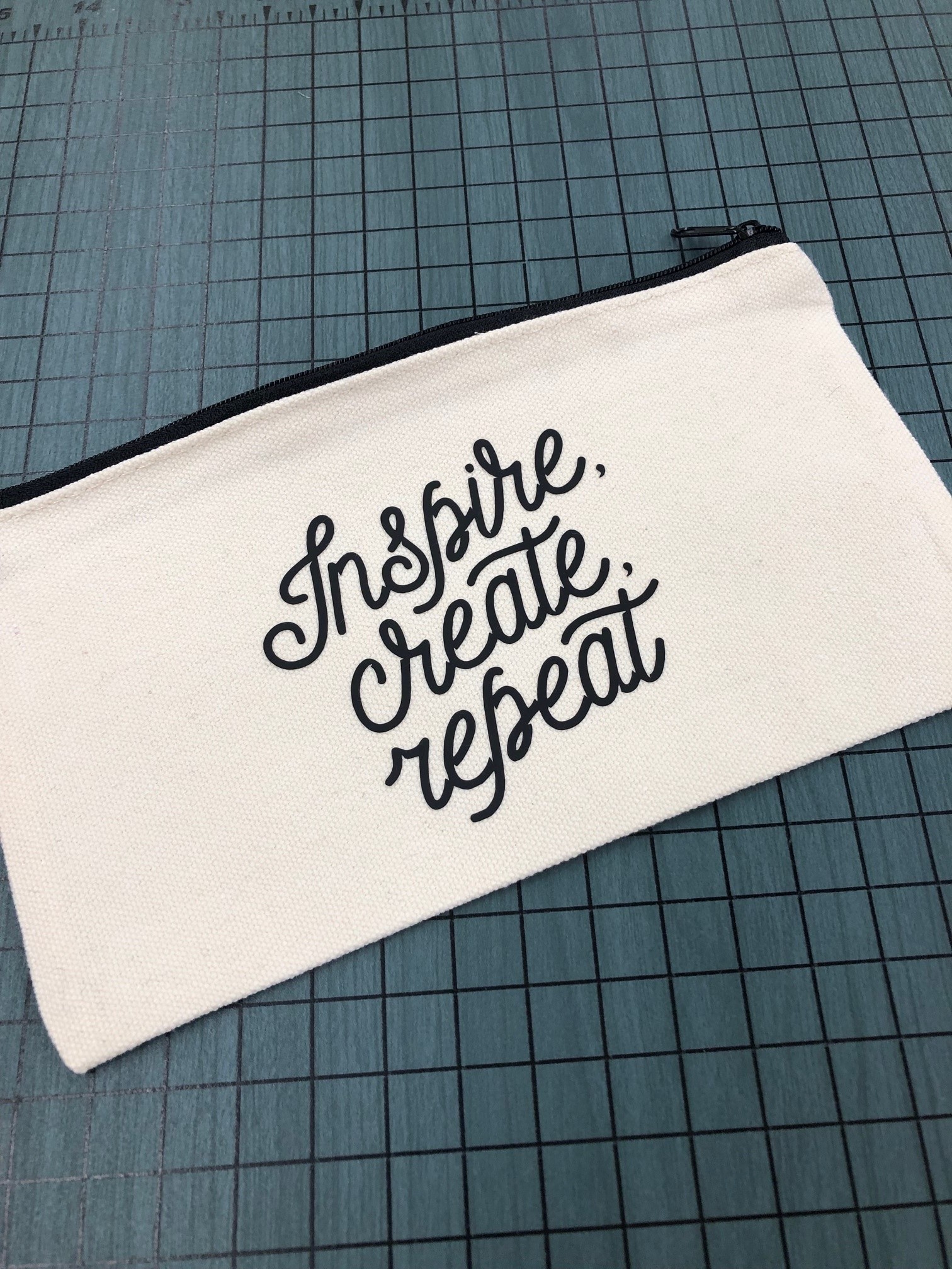 zippered pouch with words inspire, create, repeat on it