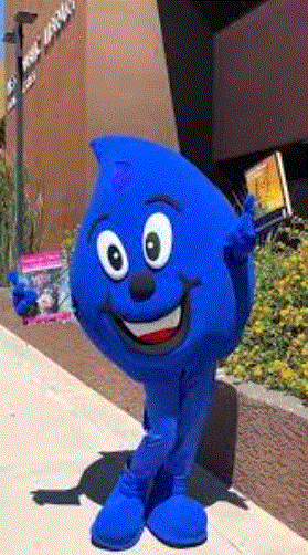Wayne Drop, Water--- Use It Wisely Mascot in from of the Main Library holding xeriscape guidebooks.  