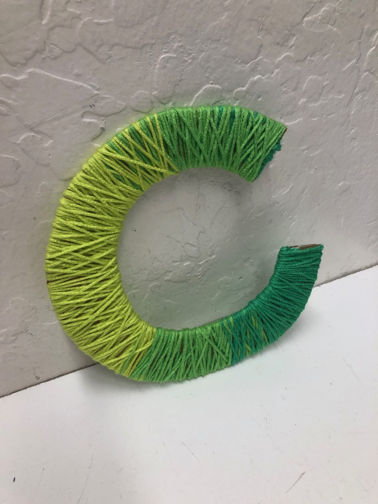 letter c wrapped in green yarn
