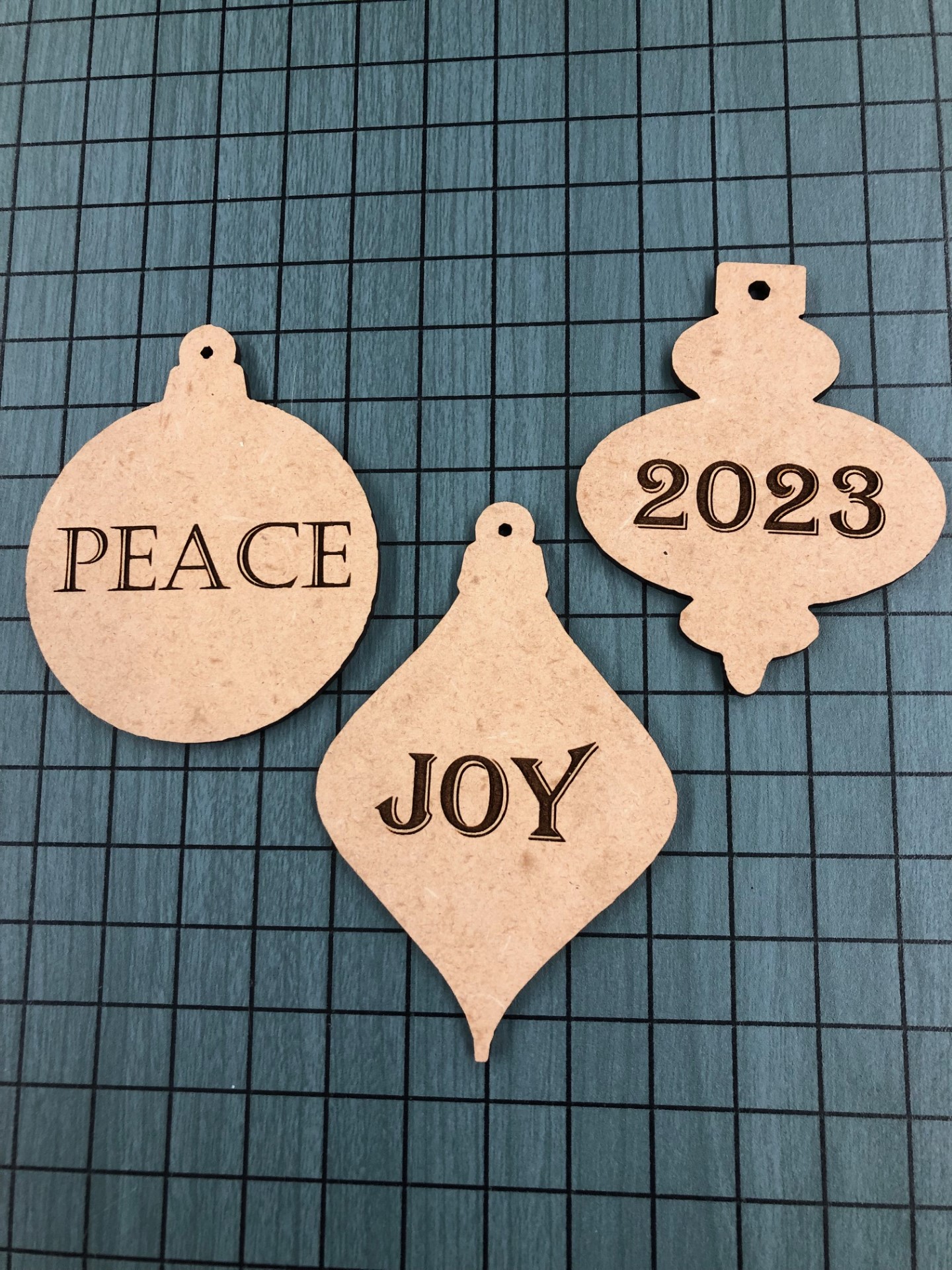 wooden ornament shapes with peace, joy 2023 engraved on them