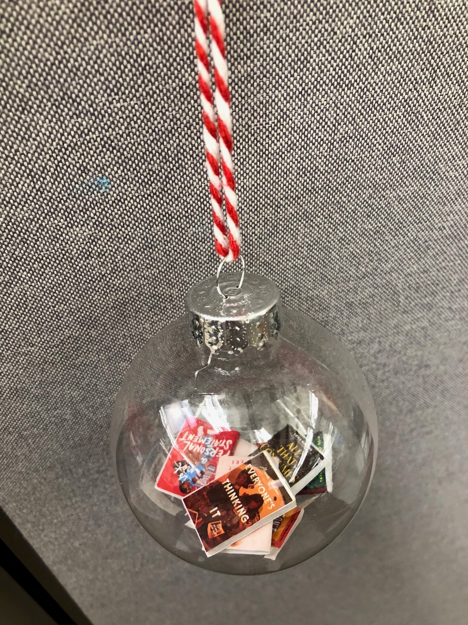 clear round christmas ornament filled with tiny copies of popular books