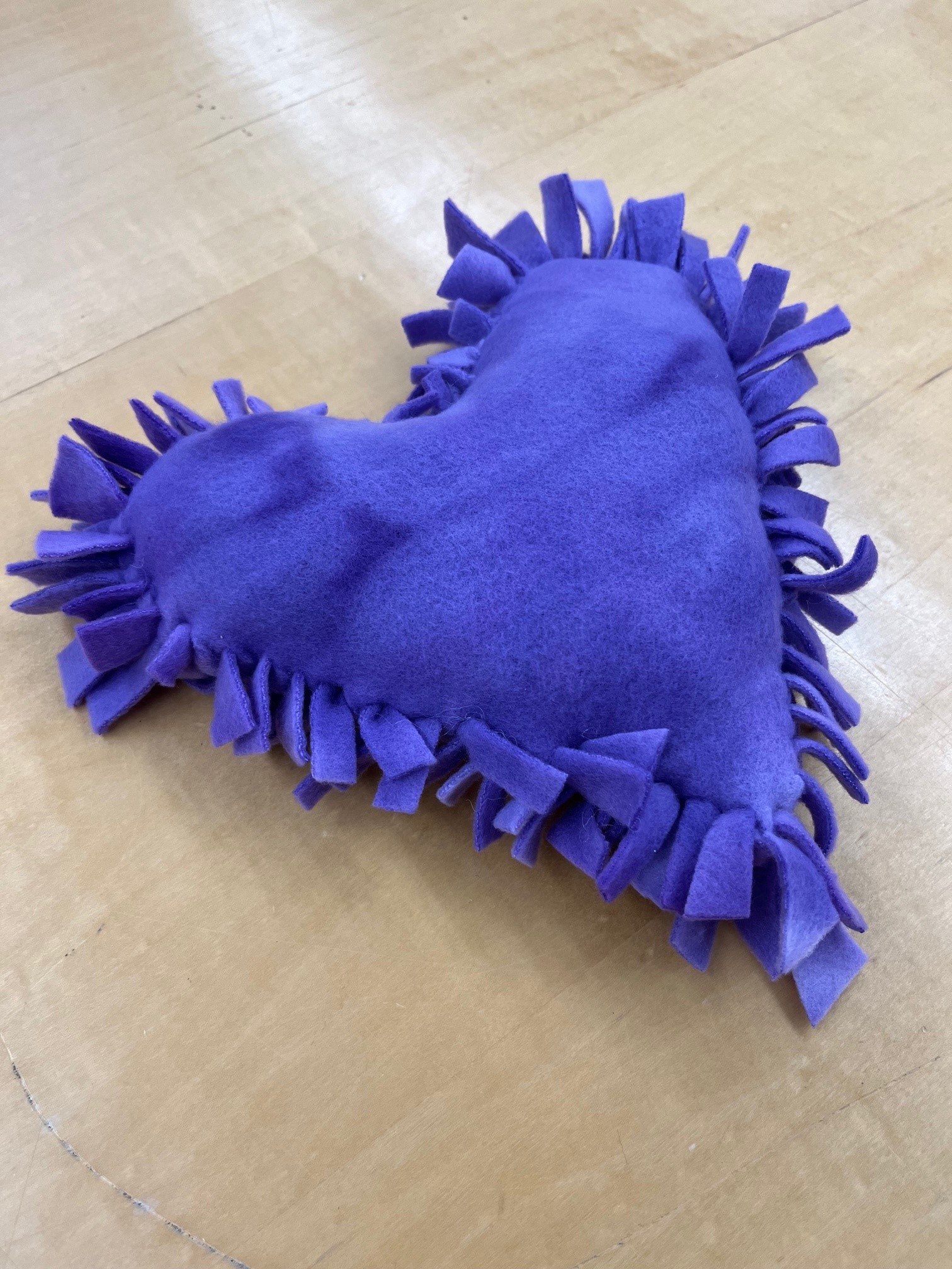 soft purple heart pillow with fringe around outside