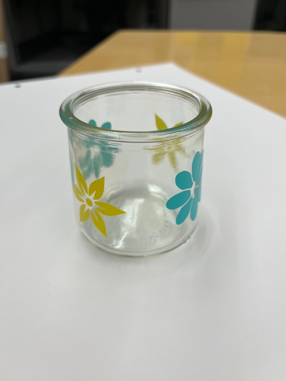 small glass jar with yellow and teal vinyl flower stickers on it