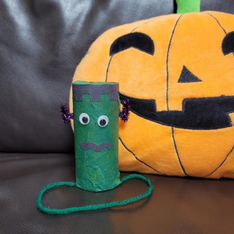 Paper tube Frankenstein prize popper sitting next to plush jack-o-lantern