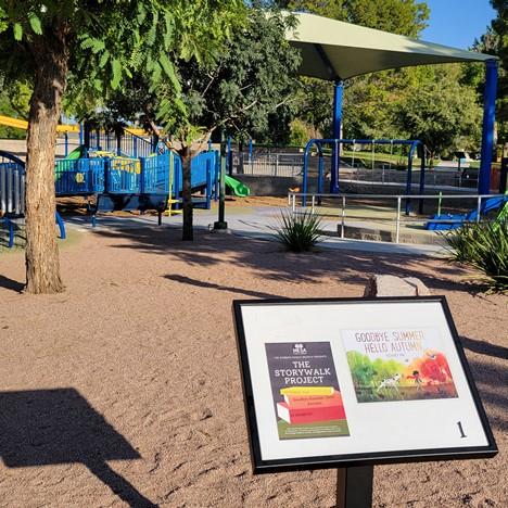 storywalk sign with Goodbye Summer, Hello Autumn cover in front of playground