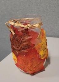 fake leaves covering mason jar with raffia string around opening