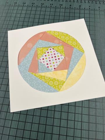 circle cut out of white paper filled with assorted strips of colored paper