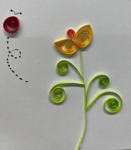 yellow flower with green stem and leaves and red ladybug made from rolled paper