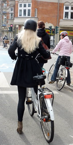 Older woman riding a bike on a busy city street 
