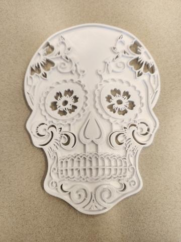 A white 3D printed flat sugar skull with raised embellishments