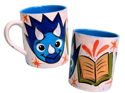 A white mug with a triceratops face and book painted on opposite sides