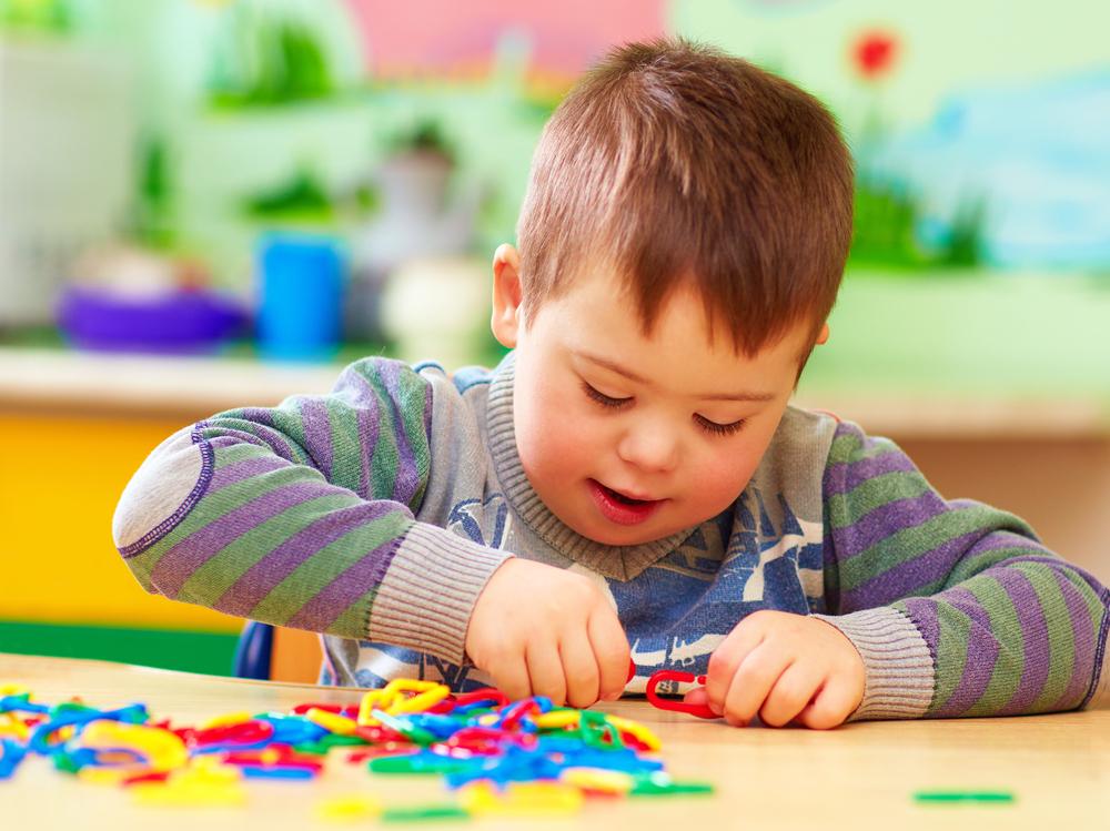 Child playing with colorful toy on a table.