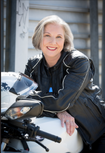 Author Michelle Cleveland posing with herself leaning forward on her white motorcycle.