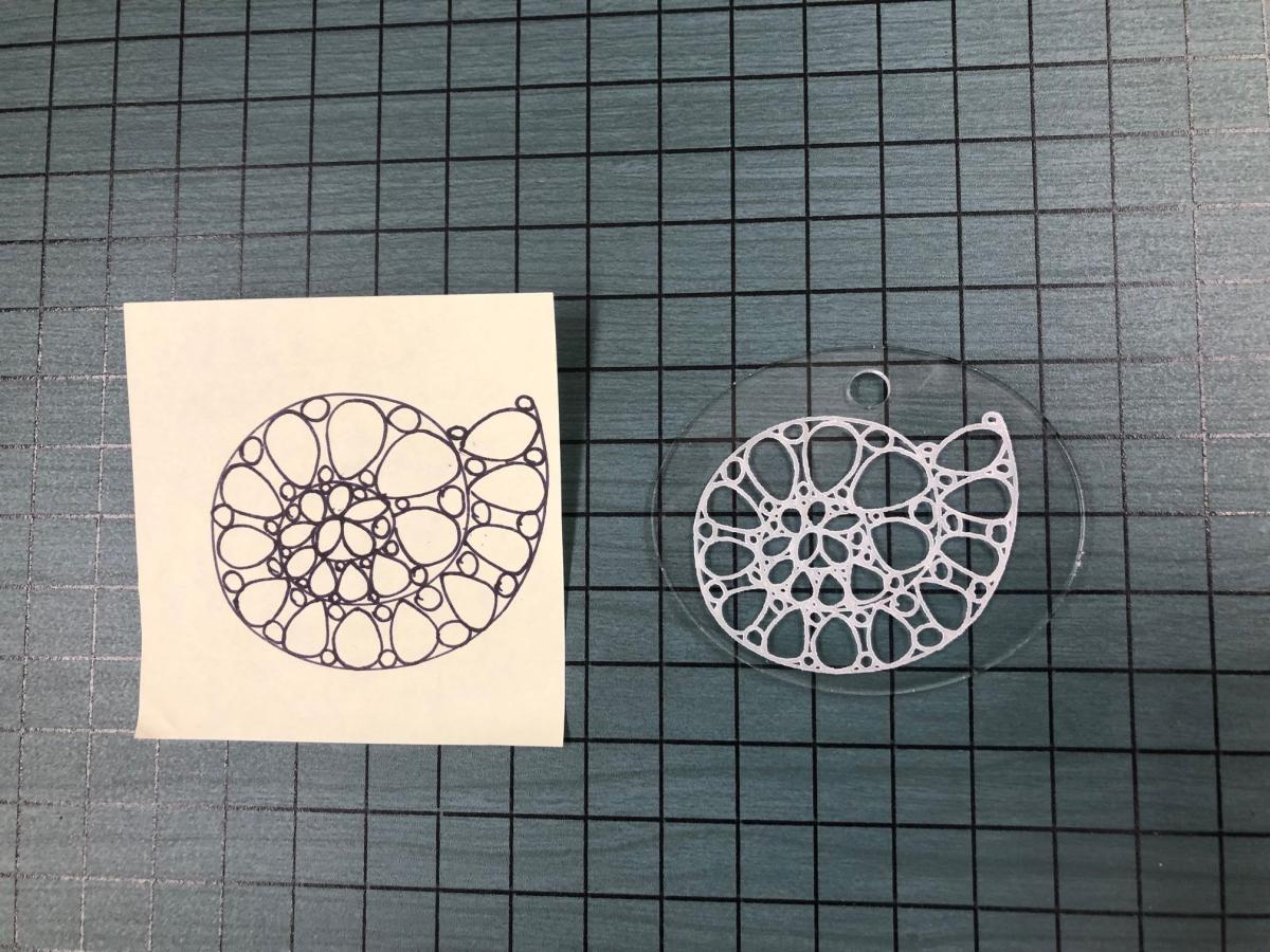 doodle of shell on paper and same image engraved on clear acrylic